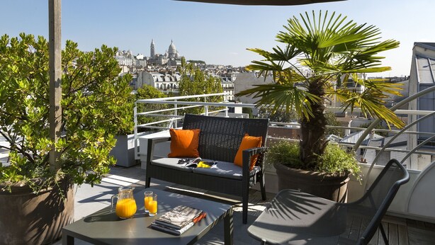 A rooftop terrace with a sofa, chairs, a table with drinks, and potted plants. - Citadines Montmartre Paris (Paris)