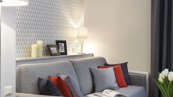Una sala de estar moderna con un sofá gris, una mesita y una lámpara.