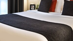 A modern hotel room with a large bed, a bedside table with a lamp, and a view of the outdoors through sheer curtains. - Citadines Montmartre Paris (Paris)