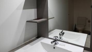 Un baño con dos lavamanos, un espejo y un estante.