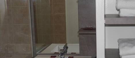 A bathroom with a white sink, a glass shower enclosure, and a towel rack with folded towels.
