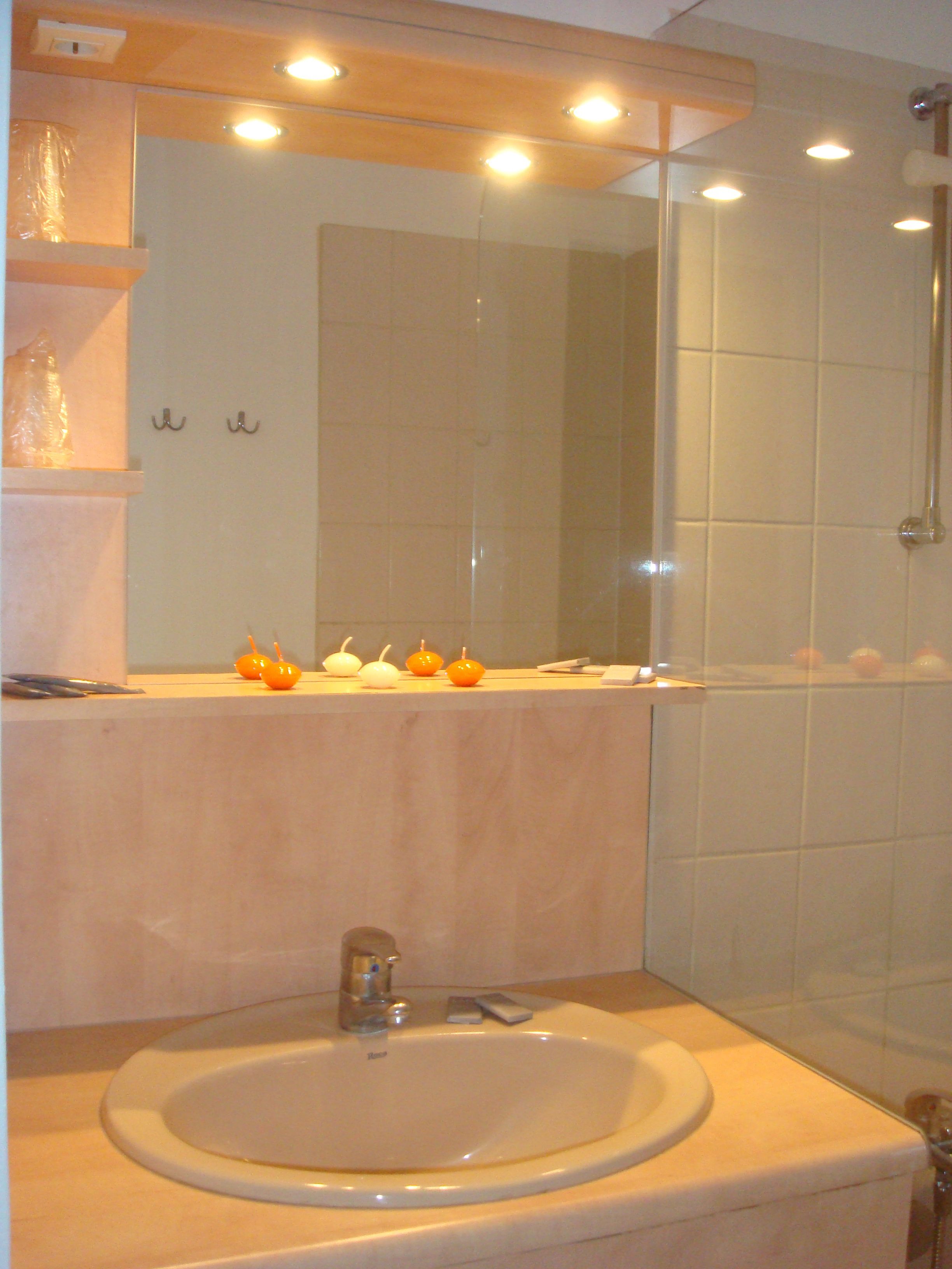 A bathroom with a sink, mirror, and shower.