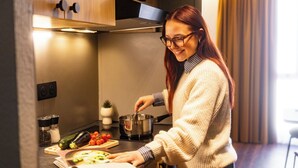 Una persona cocina en una cocina moderna con armarios de madera, una estufa y diversos utensilios de cocina.