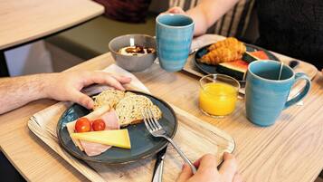 En frukostuppsättning med en tallrik mat, en mugg och ett glas apelsinjuice.