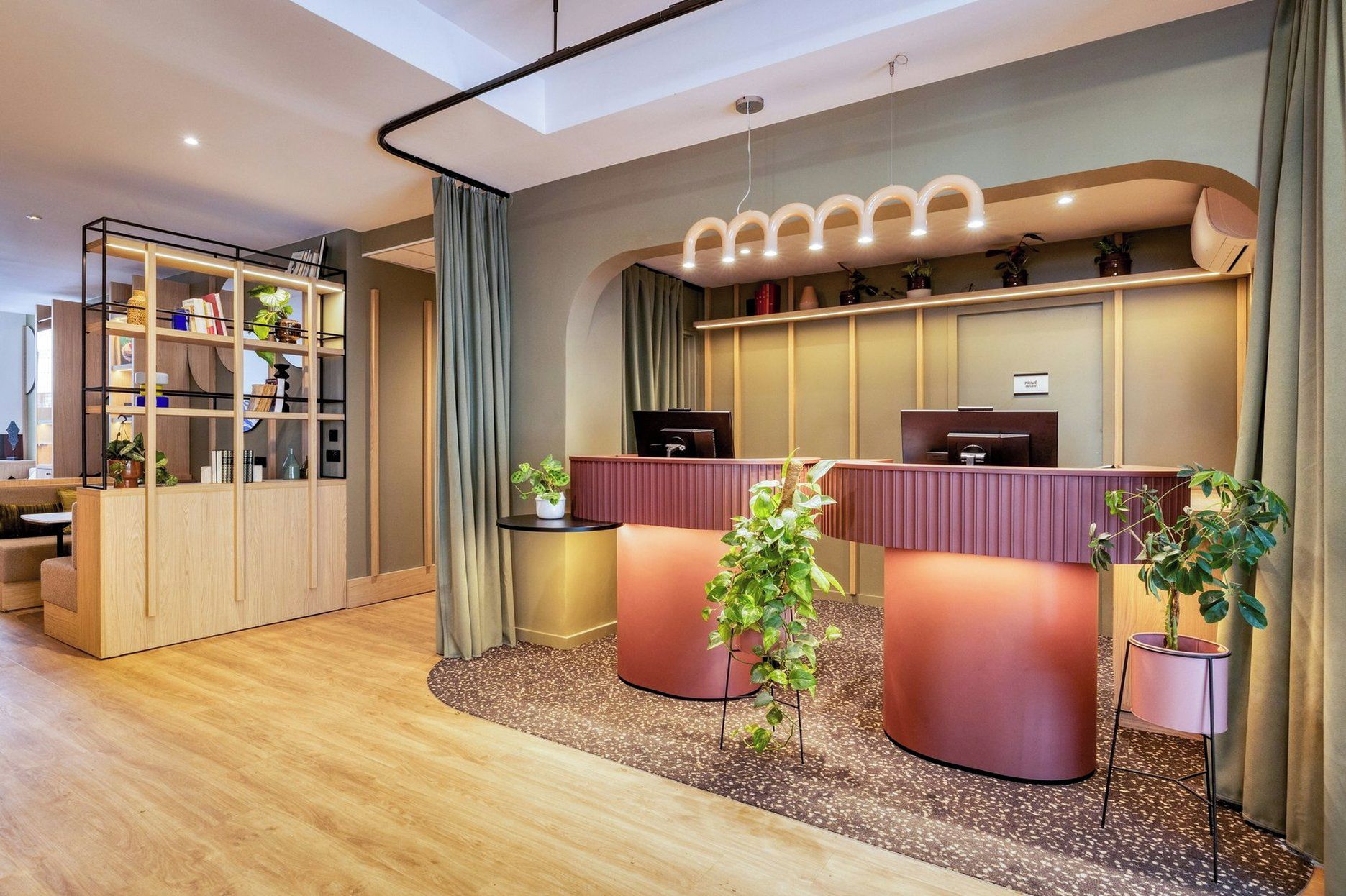 A reception area with a modern design, featuring a reception desk, a seating area with a sofa, and a bookshelf with various items.