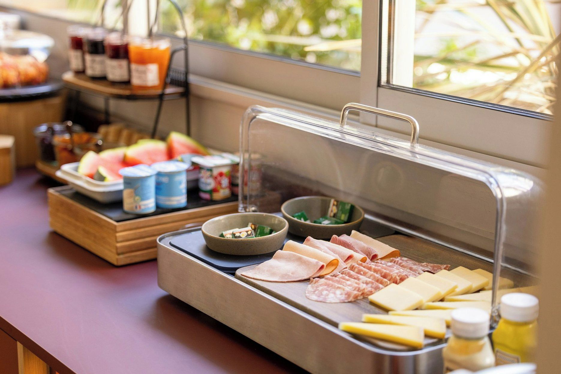 A buffet setup with various food items including meats, cheeses, and fruits.