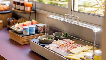 A buffet setup with various food items including meats, cheeses, and fruits.