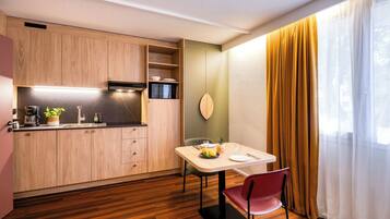 A compact kitchen with wooden cabinets, a microwave, and a dining area with a table and chairs.