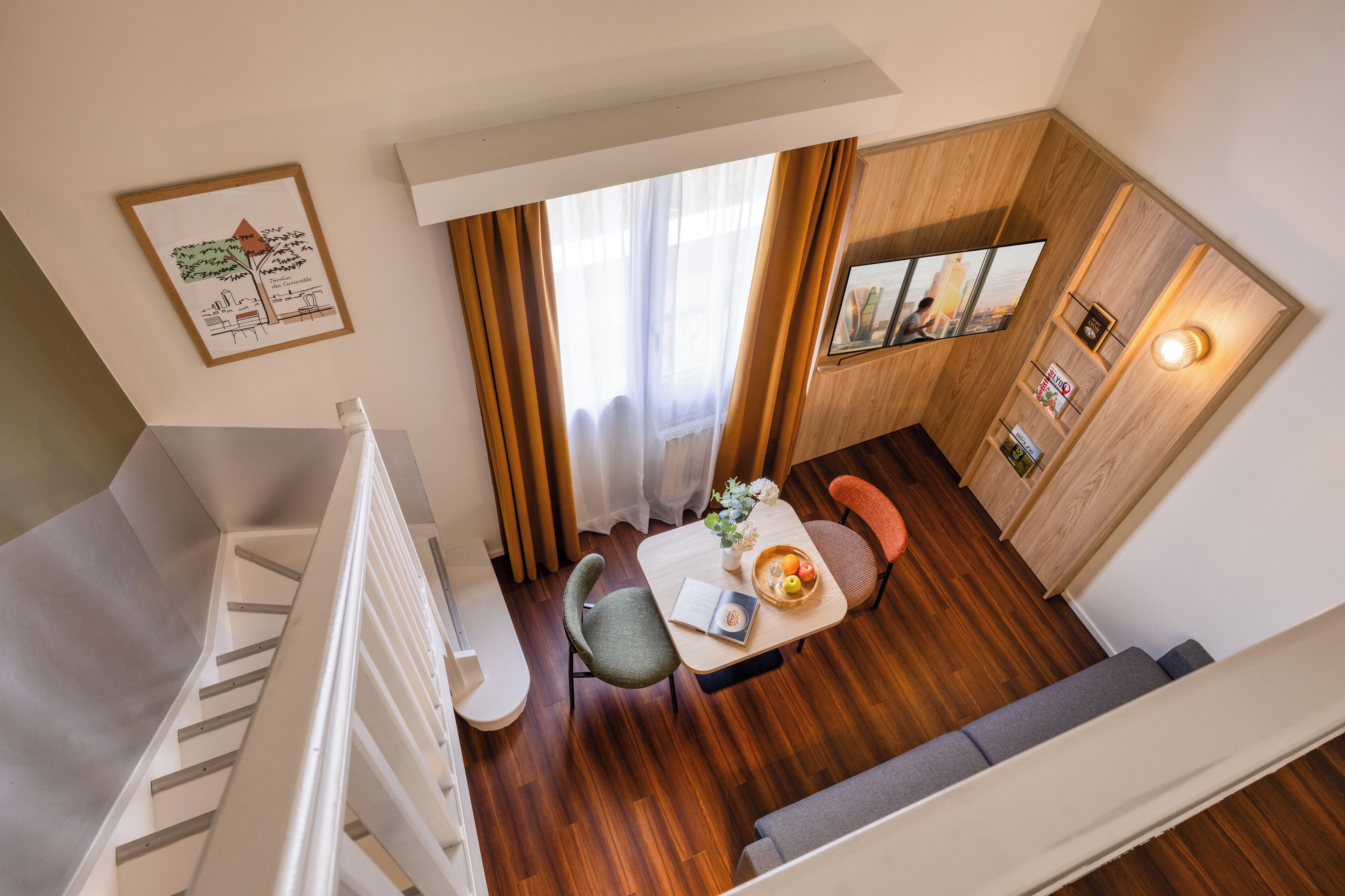 A modern interior with a staircase, a dining area with a table and chairs, a sofa, and a wooden wall with a TV and shelf.