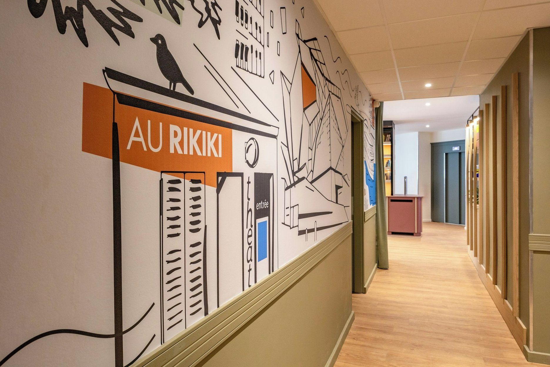 Een gang met een muurschildering met abstracte ontwerpen en een bord waarop 'AU RIKIKI' staat.