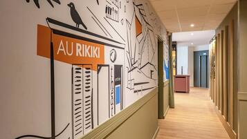 Een gang met een muurschildering met abstracte ontwerpen en een bord waarop 'AU RIKIKI' staat.
