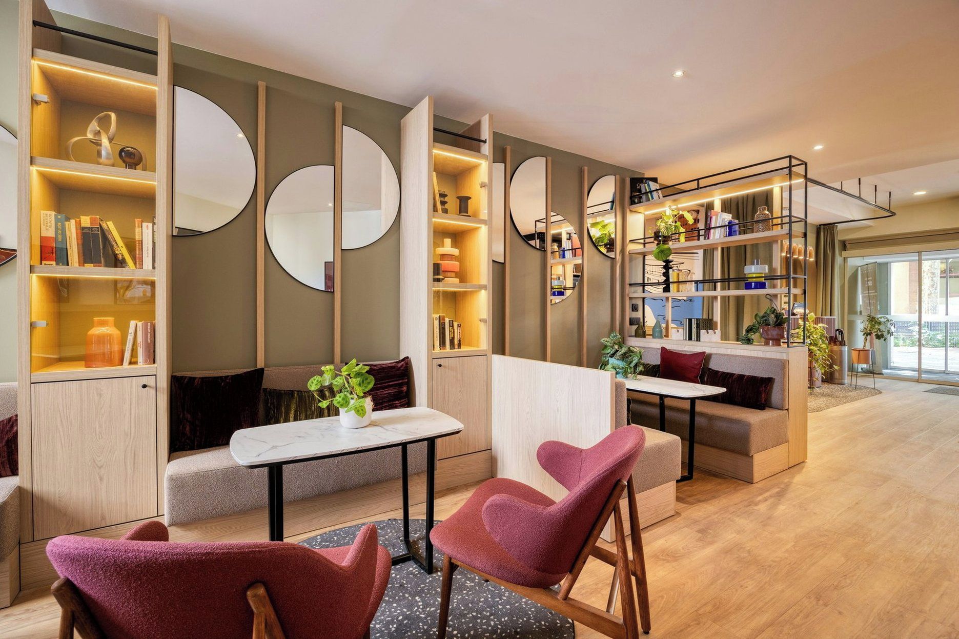 A modern interior with seating areas, bookshelves, and decorative mirrors.