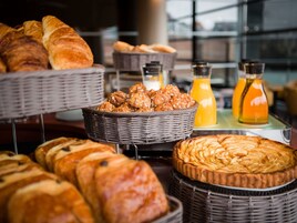 Diversas opciones de productos horneados exhibidas en cestas y sobre una mesa, con una vista a la ventana de fondo.
