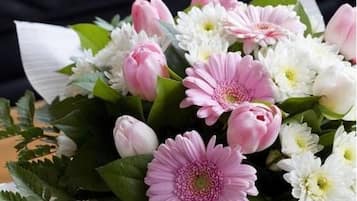 Un ramo de flores con capullos rosa y blancos y hojas verdes.