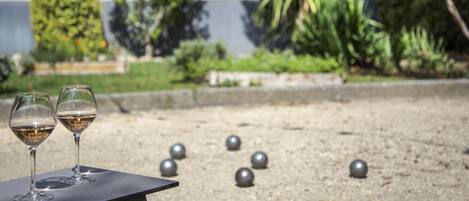 Two wine glasses on a table with a garden and a building in the background.