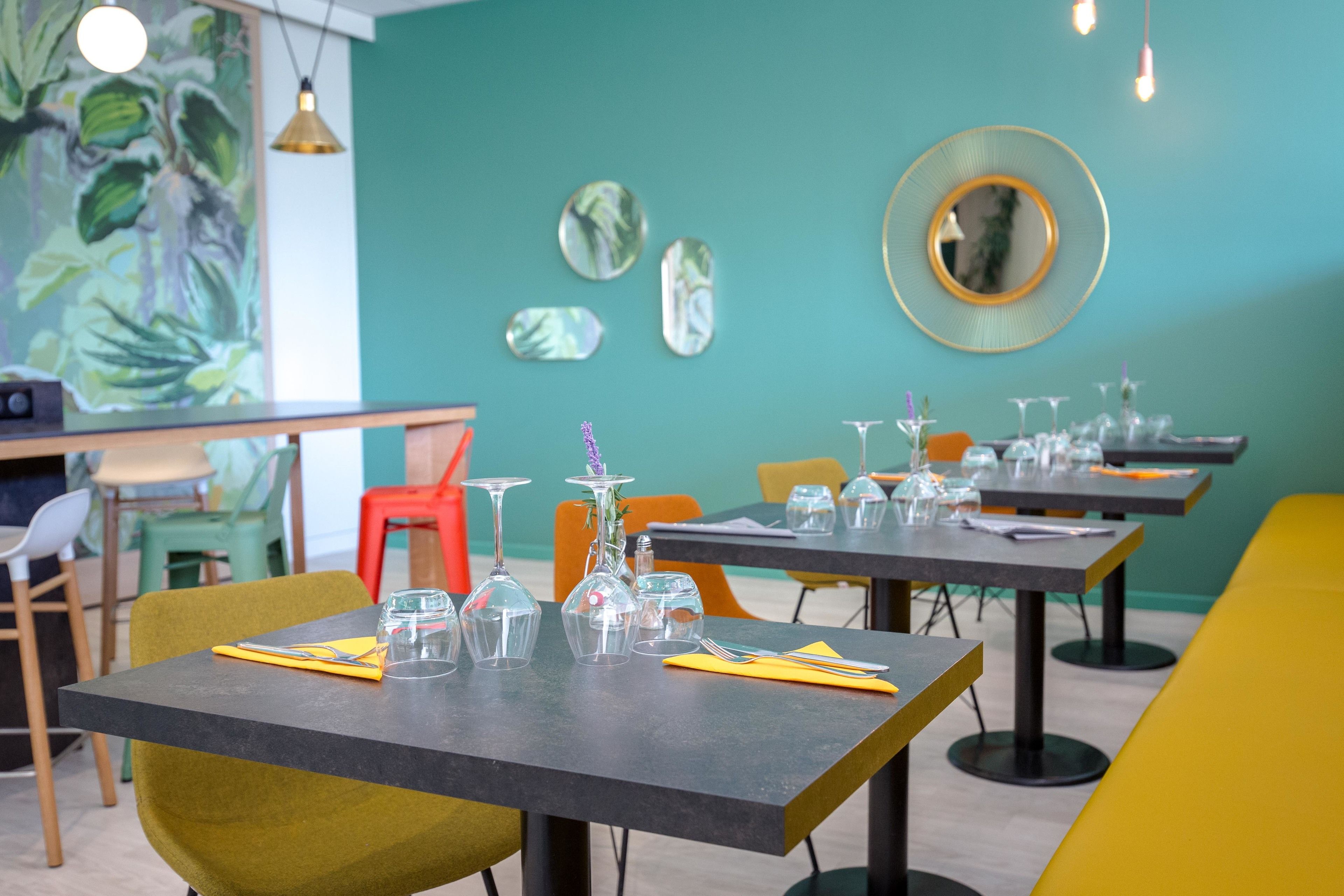 Um restaurante com mesas postas, cadeiras e um mural na parede.