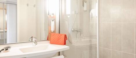 Un baño moderno con un espejo grande, un lavabo blanco, una cabina de ducha de cristal y un perchero para toallas.