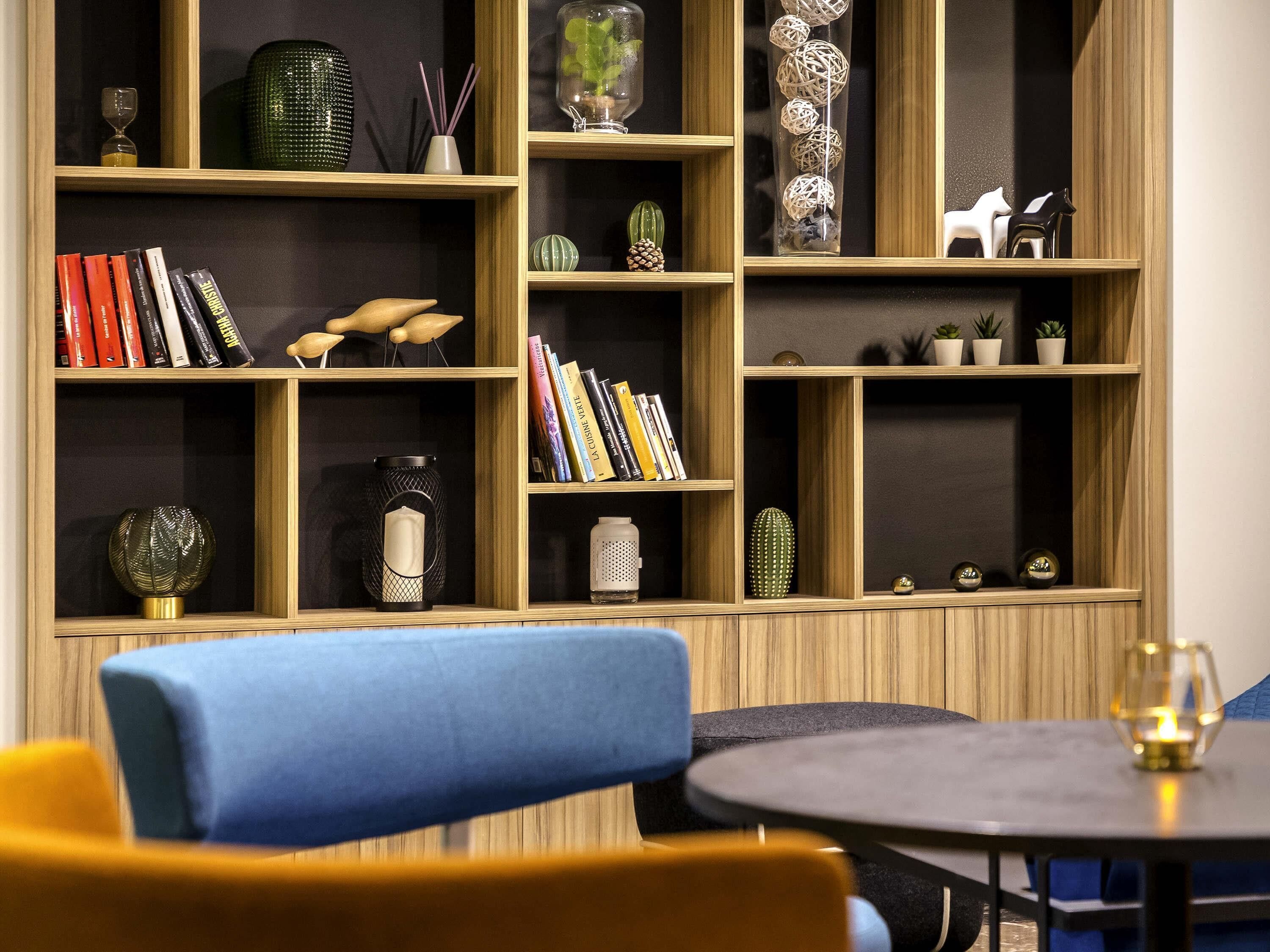 A room with a bookshelf, a round table, and a blue chair.