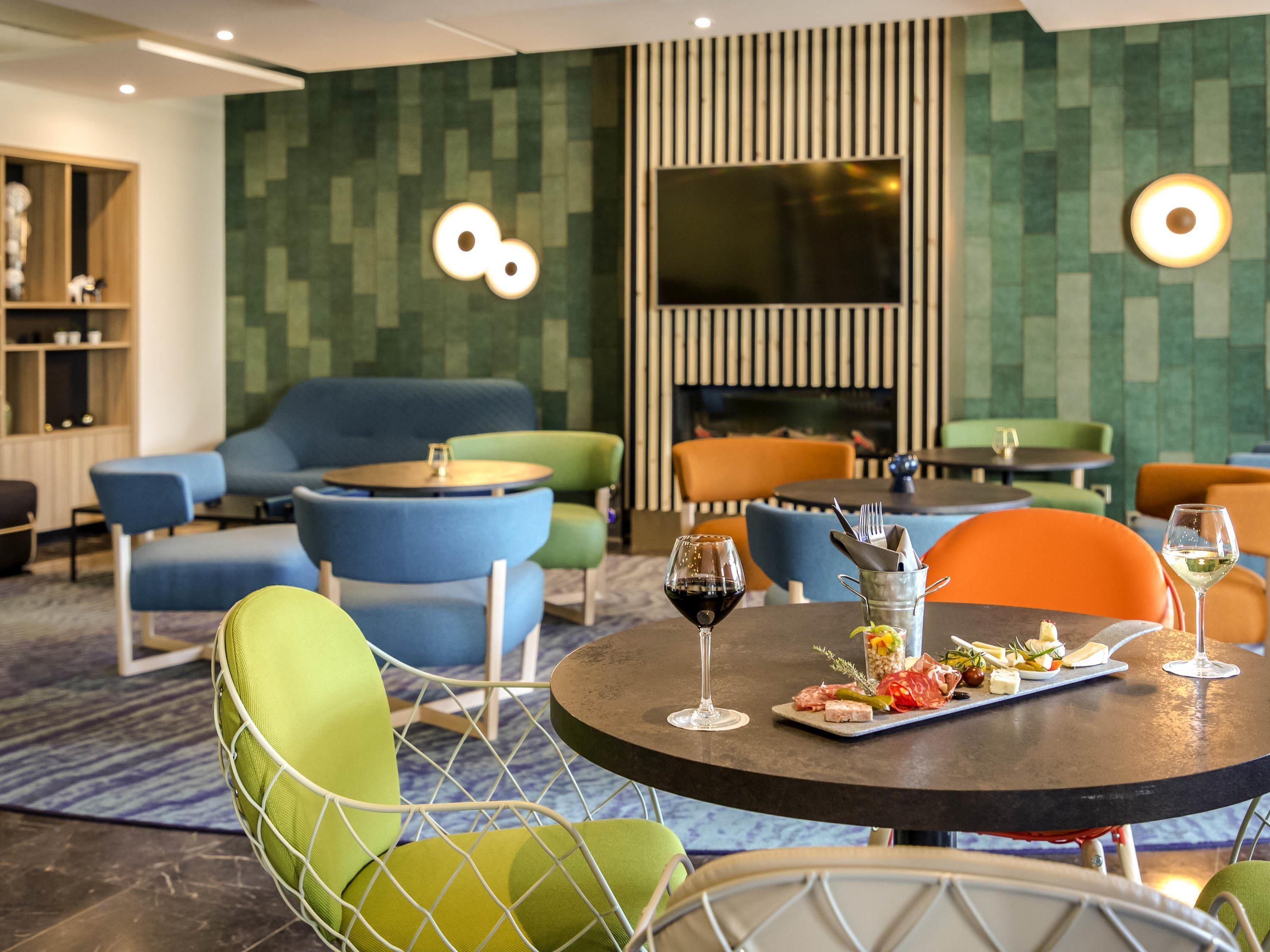A modern hotel lobby with a round table, chairs, sofas, and a large window.
