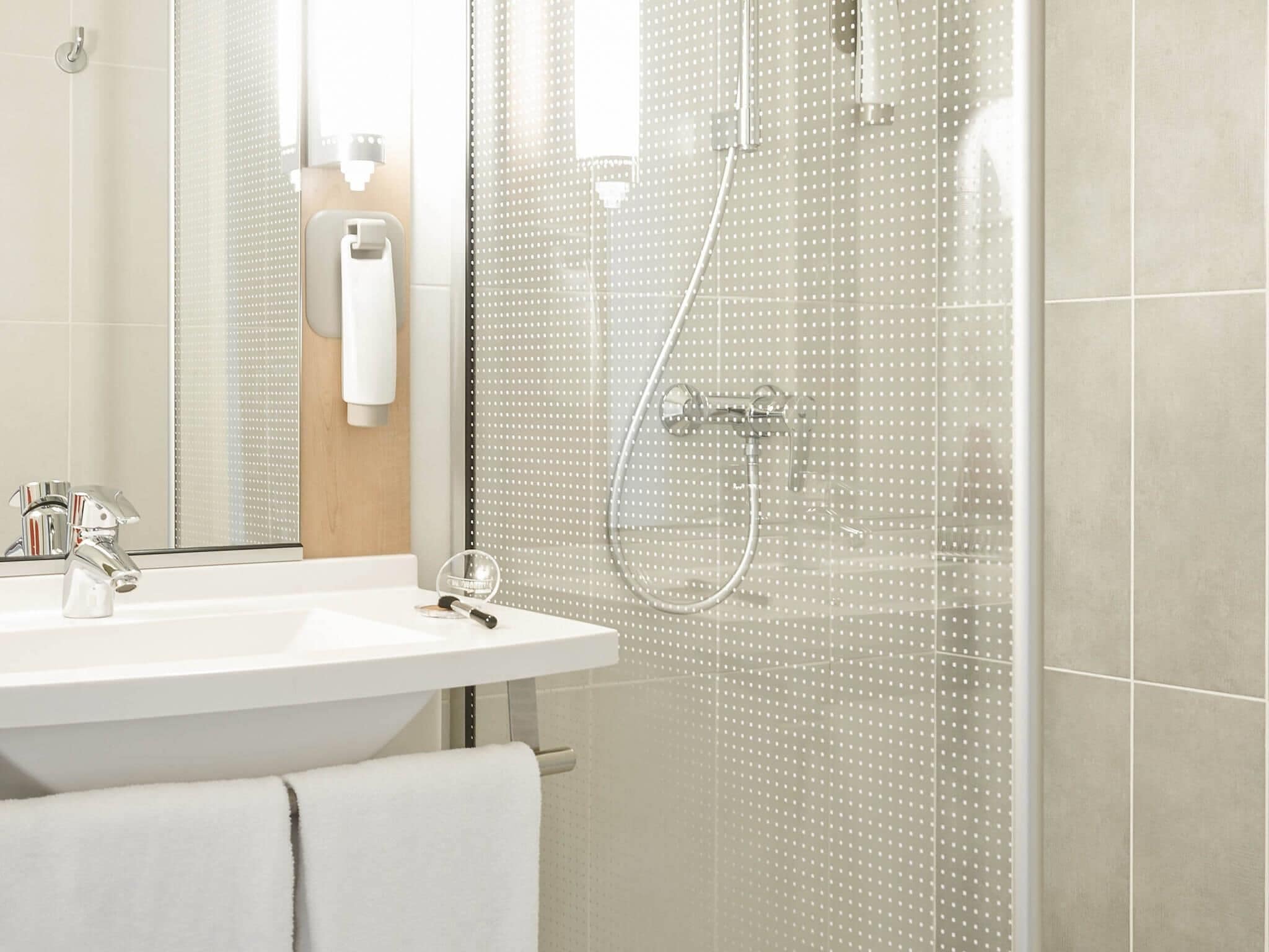 Une salle de bain moderne avec une douche à parois de verre, un lavabo blanc et un miroir.