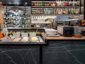 A buffet area with various food items, a coffee machine, and a bar with a wide selection of liquor bottles. - ibis Paris Ornano Montmartre Nord 18ème (Paris)