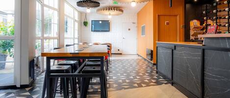 A modern interior with a wooden table and chairs, a patterned floor, and a bar area with wine bottles.