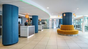 A modern lobby with a reception desk, blue pillars, a yellow seating area, and pendant lighting. - Novotel Glasgow Centre (Glasgow)