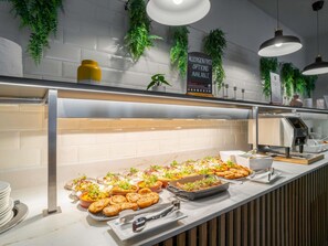A buffet with various dishes, a sign indicating allergen-free options, and a modern kitchen area with hanging plants. - Novotel Glasgow Centre (Glasgow)
