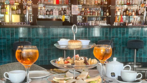 A bar area with a variety of liquor bottles, a three-tiered dessert display, and a table set for a meal with glasses and cutlery. - Novotel Glasgow Centre (Glasgow)