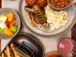 A meal with sausages, mashed potatoes, baked beans, and grilled vegetables.
