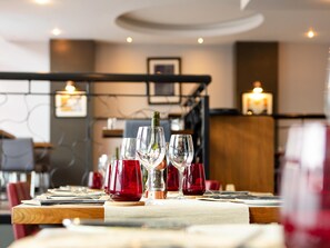 Una mesa de comedor con copas de vino y una botella, en un restaurante con una decoración moderna.