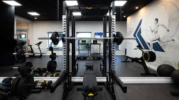 A gym with weightlifting equipment, treadmills, and a wall mural.