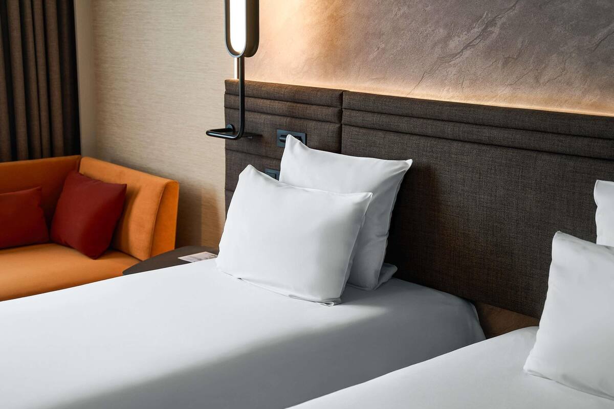 Une chambre d’hôtel avec un grand lit, un canapé et un luminaire fixé au mur.