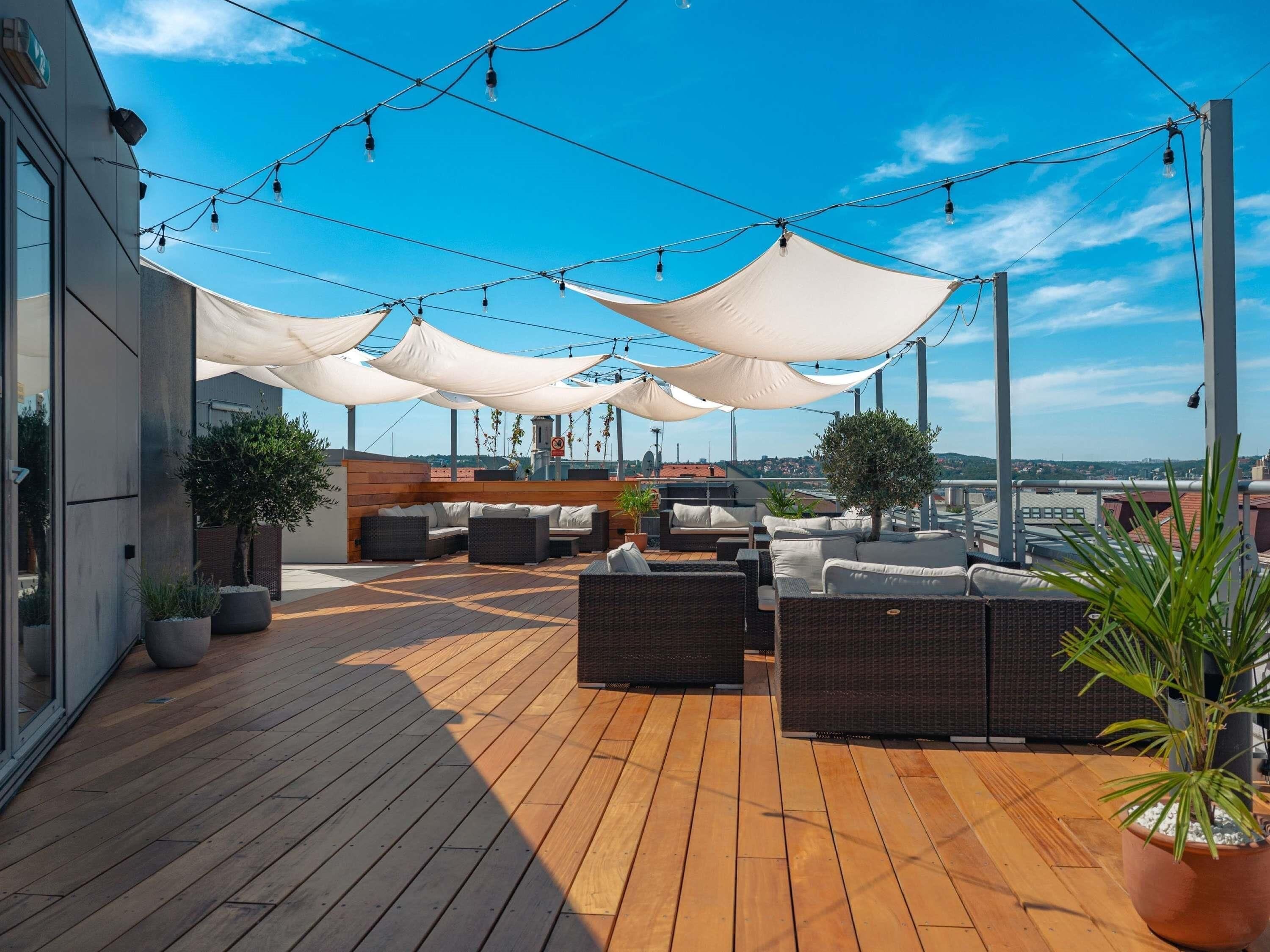 Eine Dachterrasse mit Außenplätzen, Lichterketten und Blick auf die Stadt.
