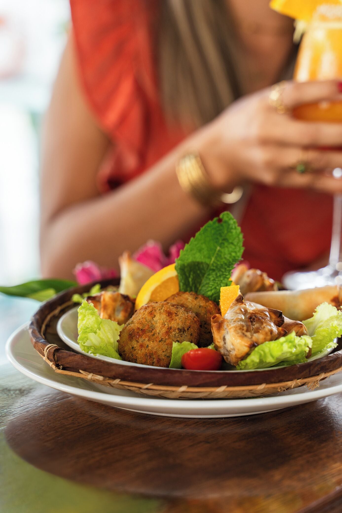 Um prato com salada, um alimento frito e uma bebida.