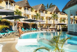 Una piscina al aire libre, sombrillas, sillones reclinables de piscina