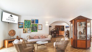A modern living room with a sofa, two wicker chairs, a coffee table, and a wooden cabinet with glass doors. - Hôtel Exsel Ermitage (Saint-Paul)