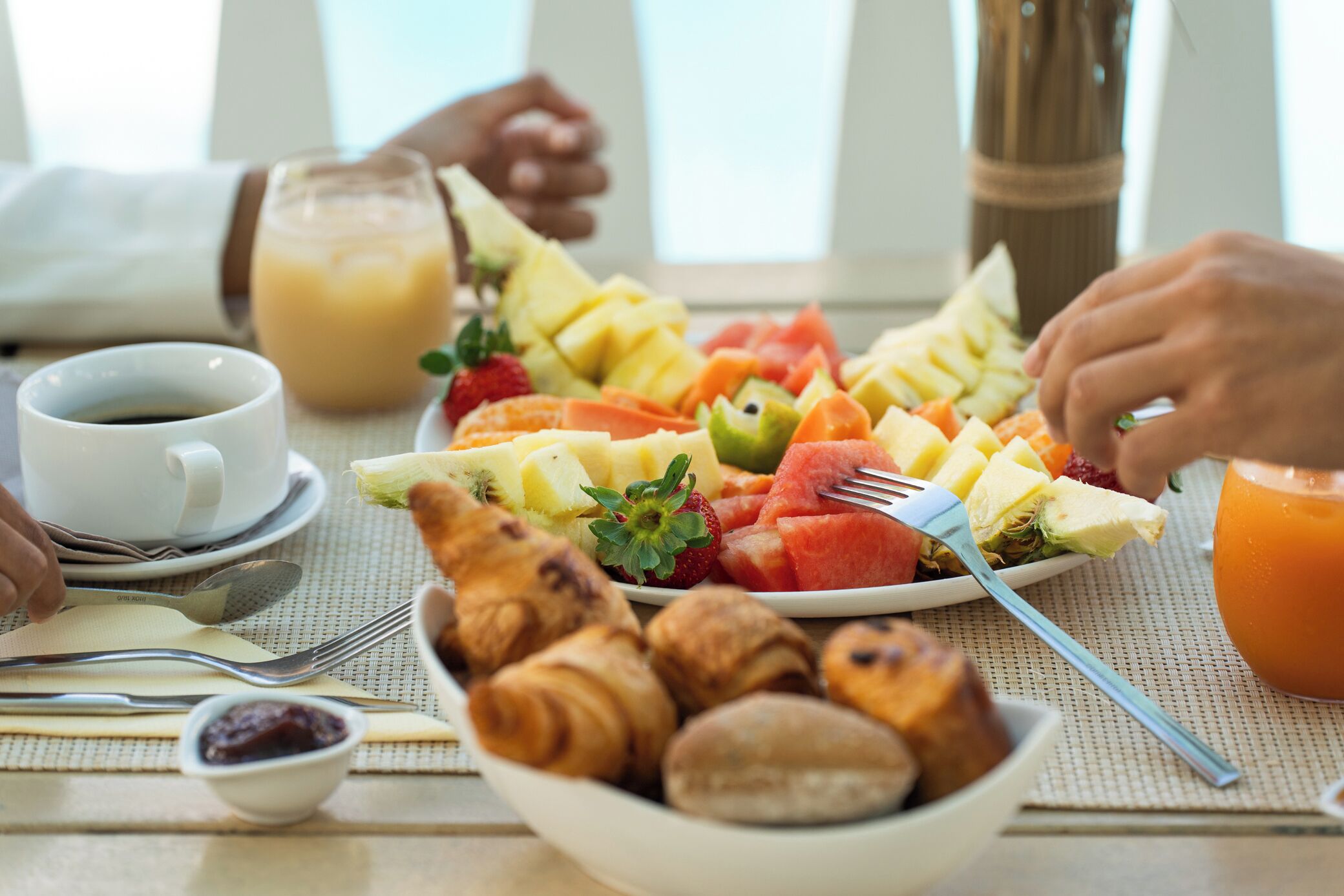 Une table dressée pour le petit-déjeuner avec des croissants, des fruits et du jus.