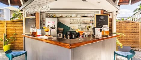 An outdoor bar area with a counter, stools, and a menu board.