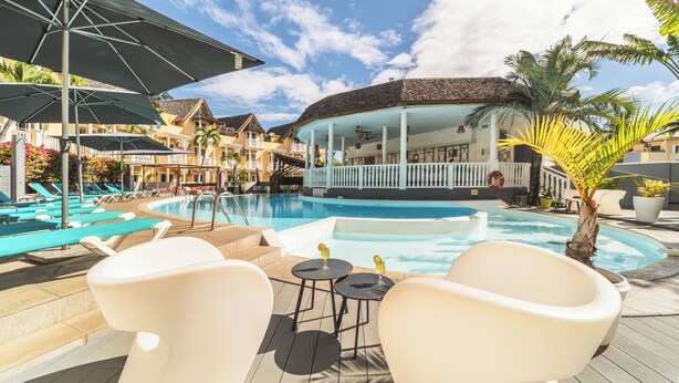 A pool area with lounge chairs, a bar area, and a covered seating area. - Hôtel Exsel Ermitage (Saint-Paul)