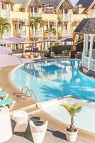 Una piscina al aire libre, sombrillas, sillones reclinables de piscina