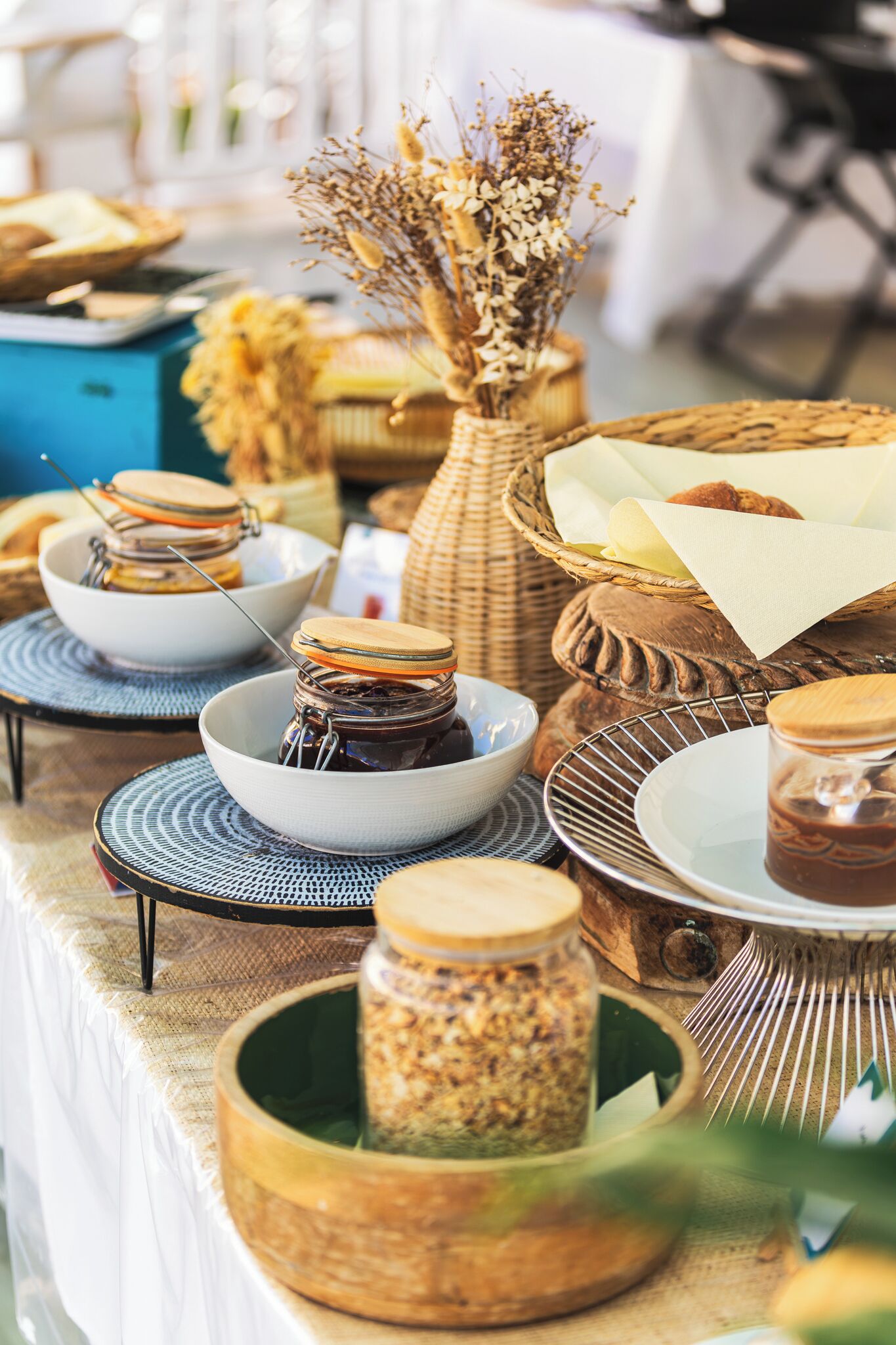 A table with various food items and containers, including jars and baskets, likely for a buffet or picnic setting.