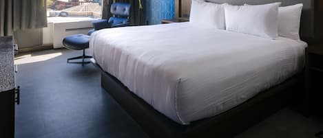 Habitación de hotel con una cama grande, un escritorio, una silla y una ventana con vistas a edificios.
