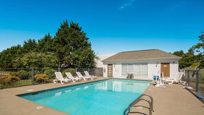 A rectangular swimming pool with a metal ladder, surrounded by white lounge chairs and a fenced area. - Quality Inn Decherd - Winchester (Decherd)