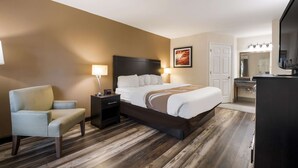 A hotel room with a bed, a chair, a nightstand, a desk, and a TV. - Quality Inn Decherd - Winchester (Decherd)