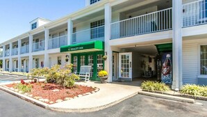 A two-story motel with a green awning labeled "Quality Inn," featuring a central entrance with a bench and potted plants. - Quality Inn Decherd - Winchester (Decherd)