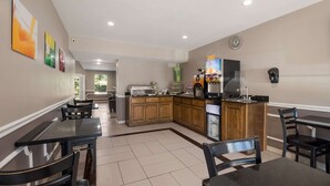 A modern dining area with black tables and chairs, a kitchen with wooden cabinets, and a refrigerator. - Quality Inn Decherd - Winchester (Decherd)