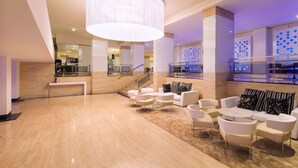 A spacious lobby with a high ceiling, a large chandelier, and a seating area with sofas and chairs. - Hotel Palma Bellver Affiliated by Meliá (Palma de Mallorca)