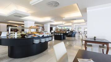 Un área de comedor de hotel moderna con mostradores tipo bufé, disposición de asientos y diseño de techo contemporáneo.