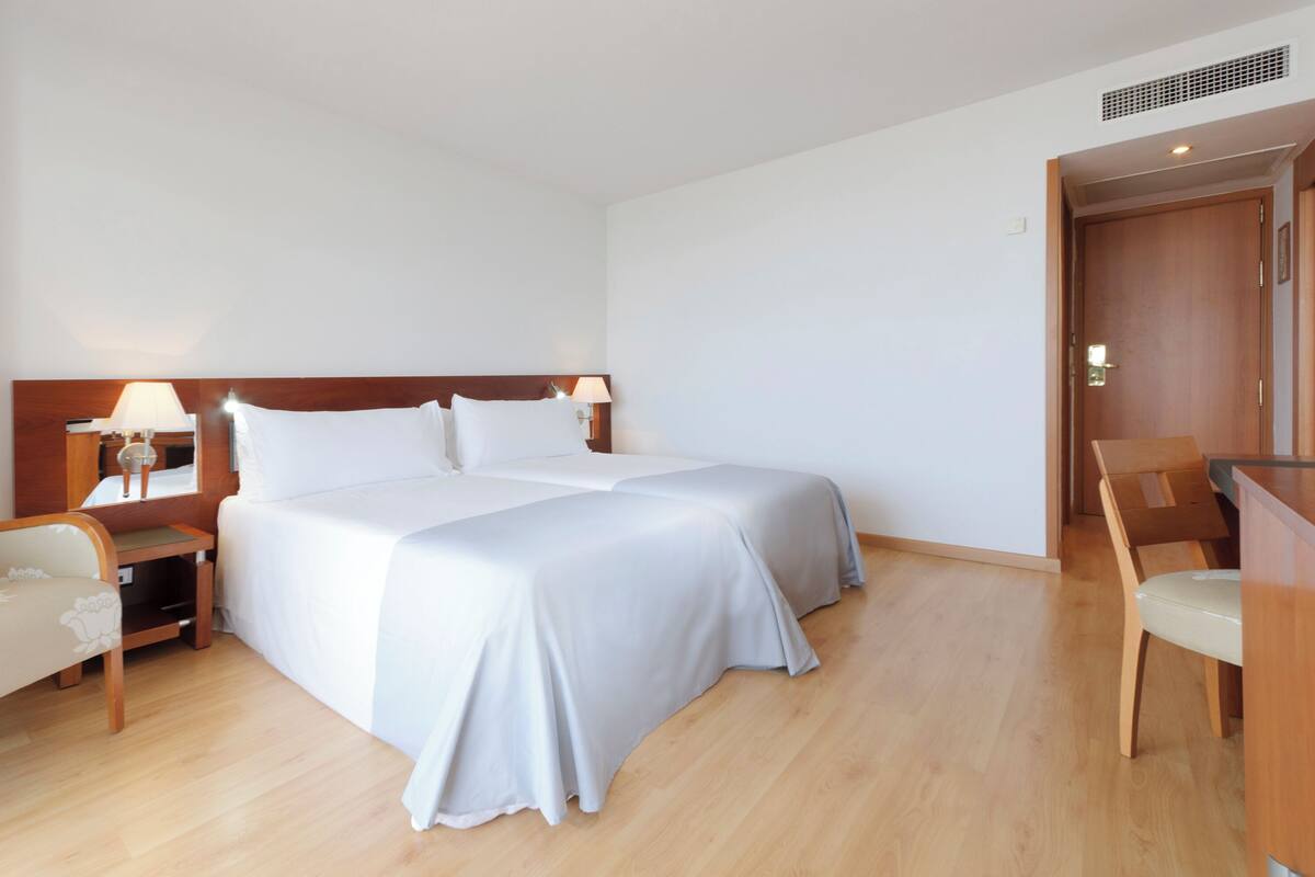 Ein Hotelzimmer mit einem großen Bett, Nachttischen, einem Sessel und einem Schreibtisch.